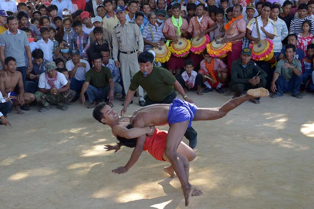 Cambodians compete in a Khmer wrestling match during the Pchum Ben festival, the festival of death, at Vihear Suor village in Kandal province on September 23, 2014. Thousands of Cambodians descended on the small village northeast of the capital on September 23 to cheer on the annual water buffalo race that marks the end of the 15-day festival for the dead. (Photo by Tang Chhin Sothy/AFP Photo)