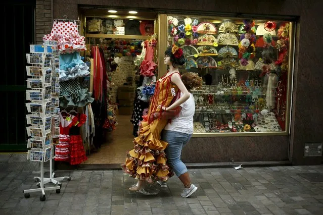 A worker carries a mannequin in a typical Sevillana dress to place it inside a clothing store in downtown Malaga, southern Spain, July 23, 2015. (Photo by Jon Nazca/Reuters)