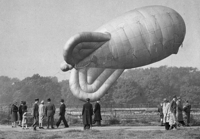 A barrage balloon in Hyde Park, London, is hauled down for inspection and to be refilled with gas, October 20, 1941. The man in uniform at left is Free French Army General Charles de Gaulle. (Photo by AP Photo)