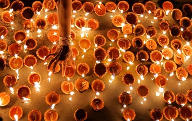 A Tamil devotee lights an oil lamp at a religious ceremony during the Diwali or Deepavali festival at Ponnambalavaneshwaram Hindu temple in Colombo, Sri Lanka on October 24, 2022. (Photo by Dinuka Liyanawatte/Reuters)