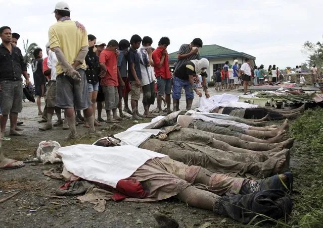 A rescuer covers bodies recovered from flashflood in New Bataan, Compostela Valley province, southern Philippines Wednesday, December 5, 2012. The death toll from Typhoon Bhopa climbed to more than 100 people Wednesday, while scores of others remain missing in the worst-hit areas of the southern Philippines. (Photo by Karlos Manlupig/AP Photo)