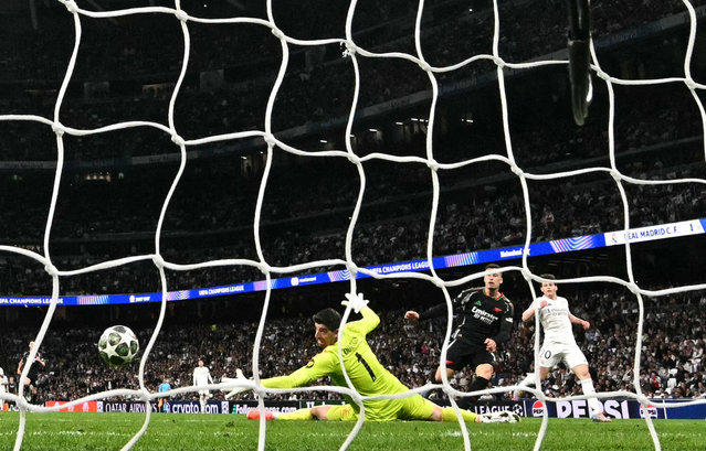 Arsenal's Brazilian midfielder #11 Gabriel Martinelli (2R) scores his team's second goal in spite of Real Madrid's Belgian goalkeeper #01 Thibaut Courtois during the UEFA Champions League quarter final second leg football match between Real Madrid CF and Arsenal at Santiago Bernabeu Stadium in Madrid on April 16, 2025. (Photo by Javier Soriano/AFP Photo)