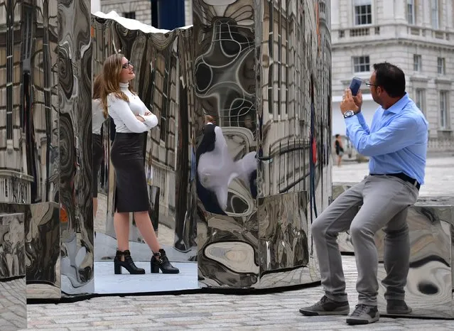 A man takes a camera phone photo of  Celine Xhixha as she poses next to an installation entitled “Bliss” created by her step-father, Helidon Xhixha, who is representing Albania at the London Design Biennale at Somerset House on September 6, 2016 in London, England. The first London Design Biennale runs from 7-27 September at Somerset House and features over 30 countries and territories. Nations from six continents will present newly commissioned works that explore the theme Utopia by Design. (Photo by Carl Court/Getty Images)