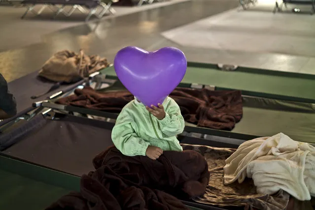 An Afghan refugee child covers his face with a balloon while he and other migrants spent the night in a shelter near Graz, Austria, Tuesday, September 22, 2015. (Photo by Muhammed Muheisen/AP Photo)