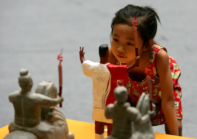 A young girl views sculpture work entitled “Prosperous Times” by artist Zhang Kaixuan is seen at an Olympic themed fine arts, calligraphy and photography exhibition at Shaanxi Art Museum in Xian of Shaanxi Province, China. (Photo by China Photos)