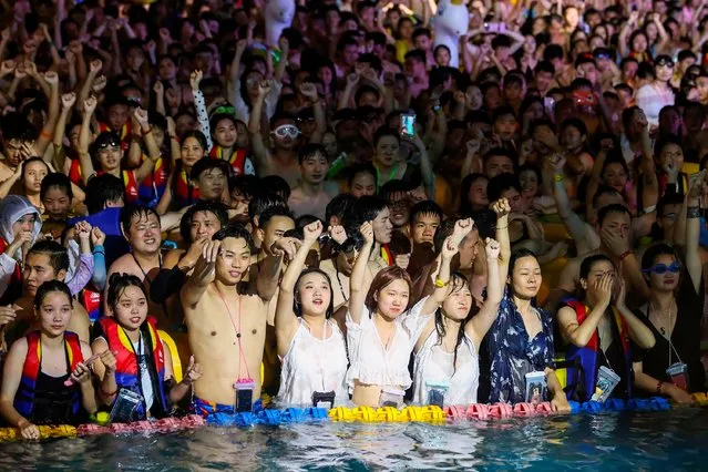 This photo taken on August 15, 2020 shows people watching a performance as they cool off in a swimming pool in Wuhan in China's central Hubei province. (Photo by AFP Photo/China Stringer Network)