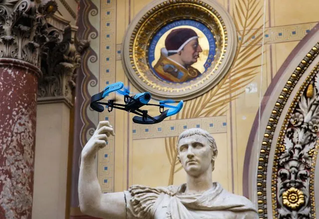 The new Bebop Parrot drone flies front of a Rome marble statue “August en Triomphateur” during a presentation to the press in Paris, France, Friday, November 7, 2014. The new Parrot Bebop drone, a quadcopter type drone with a fish eye camera benefits from an exclusive 3-axes image stabilization system that maintains a fixed angle of the view, regardless of the inclination of the drone and its movements caused by wind turbulence. (Photo by Francois Mori/AP Photo)