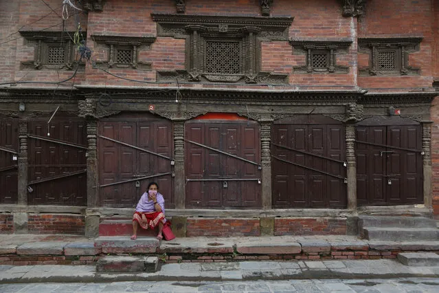 A Nepalese woman takes rest in front of a closed shop on her way back home from the market during lockdown in Kathmandu, Nepal, Tuesday, August 25, 2020. (Photo by Niranjan Shrestha/AP Photo)