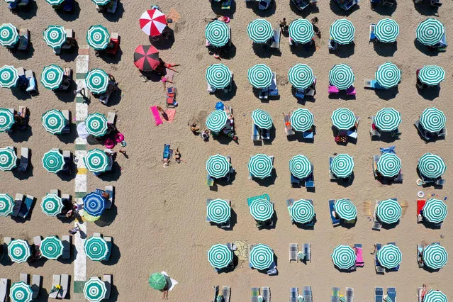 An aerial photograph taken on August 22, 2020, shows parasols on a beach of the Adriatic Sea in Durres, as a heatwave sweeps through Europe. Due to the Covid 19 pandemic, the number of tourists entering Albania dropped by 66 percent. The majority of tourists are domestic or from the neighbouring Kosovo and North Macedonia. (Photo by Gent Shkullaku/AFP Photo)