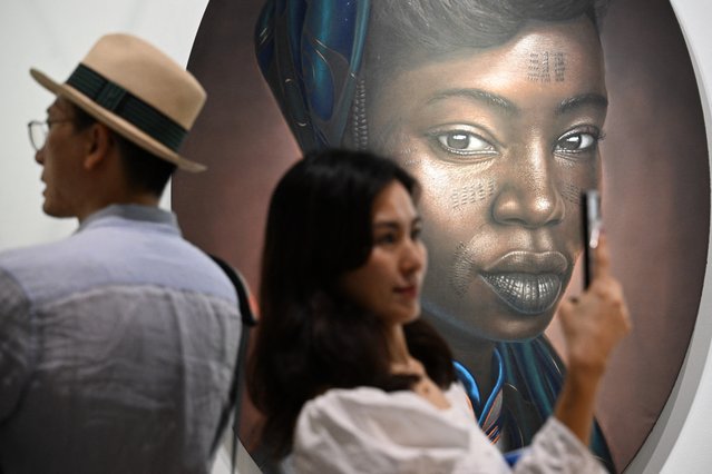 A visitor takes photos of works by Nigerian artist Babajide Olatunji at Art Basel in Hong Kong on March 27, 2024. (Photo by Peter Parks/AFP Photo)