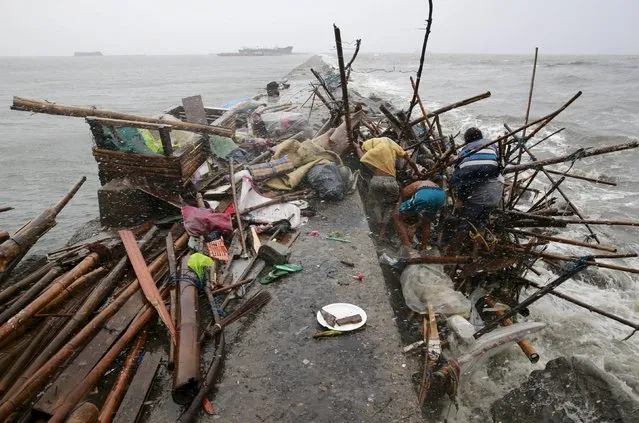 A Taroyo family living along the coast of Manila Bay searches for salvageable items after their house was damaged  by strong winds brought by typhoon Koppu on October 18, 2015. (Photo by Romeo Ranoco/Reuters)