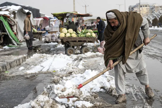 An Afghan vegetable vendor shovels snow along a street in Kabul on January 23, 2023. (Photo by Wakil Kohsar/AFP Photo)
