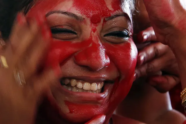 An Indian woman smiles as others apply vermillion paste on her face during celebrations marking Durga Puja festival in Mumbai, India, Thursday, October 22, 2015. The festival commemorates the slaying of a demon king by lion-riding, 10-armed goddess Durga, marking the triumph of good over evil. (Photo by Rajanish Kakade/AP Photo)
