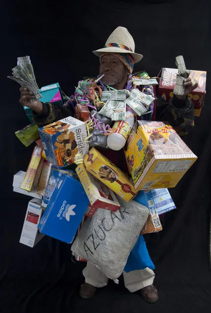 In this February 3, 2018 photo, Hilarion Macias, dressed as “Ekeko”, the god of prosperity and the central figure of the Alasita Fair, holds fake money as he poses for a portrait in La Paz, Bolivia. Macias, 55, uses coca leaves to read people's futures. “The Ekeko is a big tradition, representing our future and a cultural tradition from the times of the Incas”, he said. Macias competed in this year's Ekeko costume competition. (Photo by Juan Karita/AP Photo)