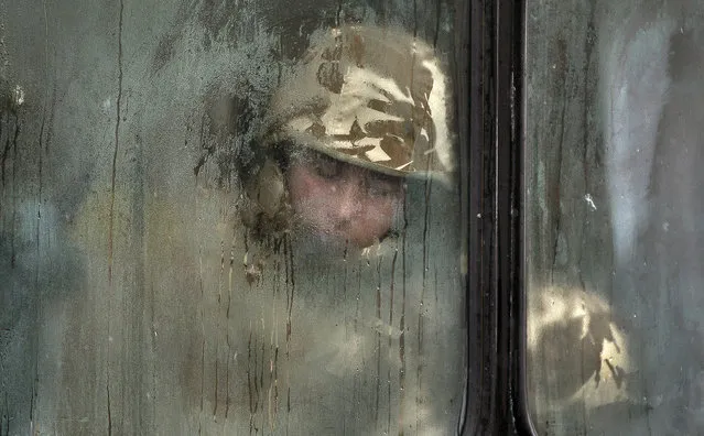 A Romanian soldier sleeps on a bus before taking part in a military parade to mark Romania's national day in Bucharest, Romania, Monday December 1, 2014. Romanians braved  the cold weather to watch the traditional armed forces parade, held outside the Palace of Parliament formerly the House of the People, built during the rule of communist dictator Nicolae Ceausescu. (Photo by Vadim Ghirda/AP Photo)