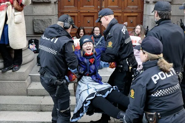 Activists are carried away by the police during a protest against a wind farm they say hinders the rights of the Sami Indigenous people to raise reindeer in Arctic Norway, in Oslo, Thursday, March 2, 2023. (Photo by Alf Simensen/NTB Scanpix via AP Photo)