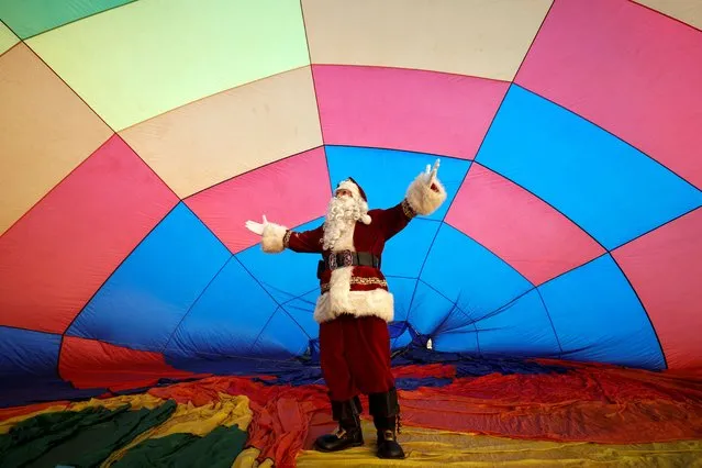 Issa Kassissieh dressed as Santa Claus gestures in front of the hot air balloon before flying above Jerusalem on December 20, 2022. (Photo by Amir Cohen/Reuters)