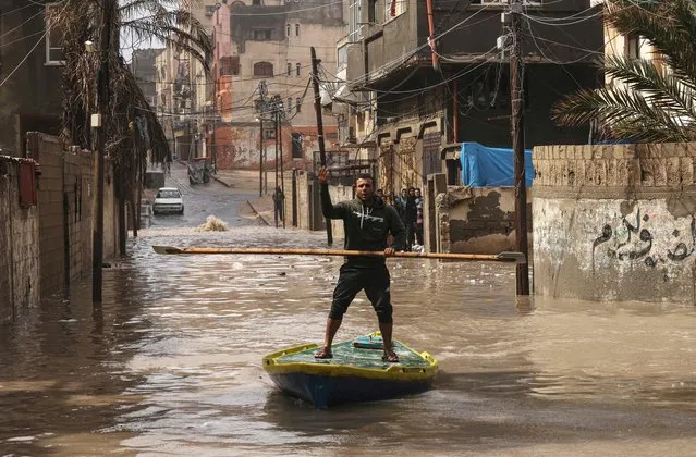 A Palestinian man rides a paddle board on a flooded street following heavy rain at the Al-Shati refugee camp in the Gaza strip on March 20, 2023. (Photo by Mohammed Abed/AFP Photo)