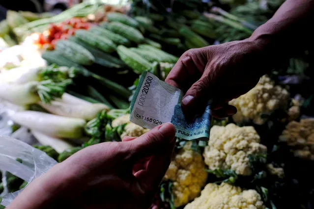A vegetable vendor (R) takes money from customer at a morning market in Jakarta, Indonesia, October 3, 2016. (Photo by Reuters/Beawiharta)