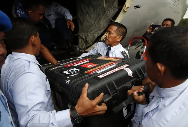 An Indonesian Air Force flight crew lift a case containing the flight data recorder from AirAsia QZ8501 onto a military plane for transport back to Jakarta at the airbase in Pangkalan Bun, Central Kalimantan January 12, 2015. (Photo by Darren Whiteside/Reuters)