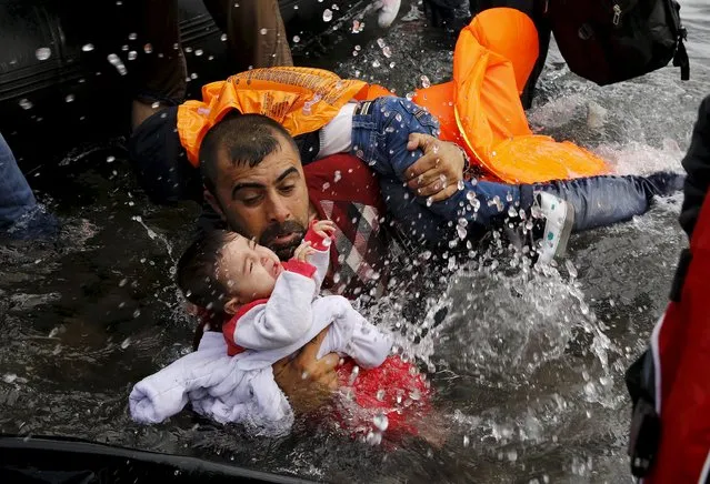 A Syrian refugee holds onto his children as he struggles to get off a dinghy on the Greek island of Lesbos, after crossing a part of the Aegean Sea from Turkey to Lesbos September 24, 2015. (Photo by Yannis Behrakis/Reuters)