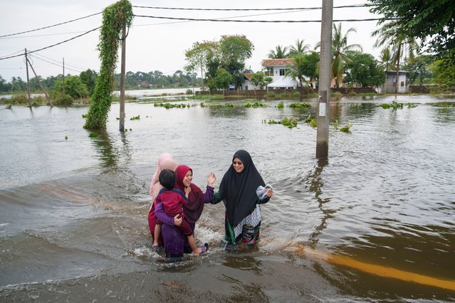 People wade through flood waters in Tumpat, outskirts of Kota Bahru, Malaysia, Tuesday, December 3, 2024. (Photo by Vincent Thian/AP Photo)