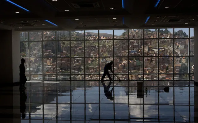 In this May 15, 2018 photo, a worker mops the floor inside Bolivia's new presidential palace, in La Paz, Bolivia. President Evo Morales will open the new 28-floor presidential palace, that includes a helipad, a suite with a Jacuzzi, massage room and gym, that has cost just over 34 million dollars of South America's poorest nation. (Photo by Juan Karita/AP Photo)