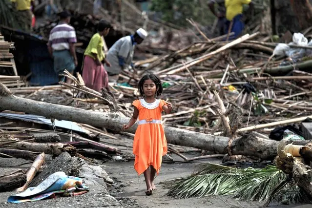 A girl walks past destroyed houses at Basara refugee camp in Sittwe on May 16, 2023, after cyclone Mocha made a landfall. The death toll in cyclone-hit Myanmar's Rakhine state rose to at least 41 on May 16, 2023, local leaders told AFP. (Photo by Sai Aung Main/AFP Photo)