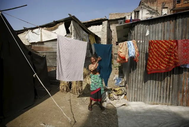 An earthquake victim hangs clothes out to dry in the sun outside temporary shelters built near houses damaged during an earthquake earlier this year, in Bhaktapur, Nepal November 19, 2015. (Photo by Navesh Chitrakar/Reuters)