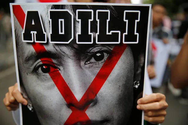 A protester holds a poster with a defaced image of Nobel Peace Prize winner Aung San Suu Kyi during a demonstration against what protesters say is the crackdown on ethnic Rohingya Muslims in Myanmar, in front of the Myanmar embassy in Jakarta, Indonesia November 25, 2016. (Photo by Reuters/Beawiharta)