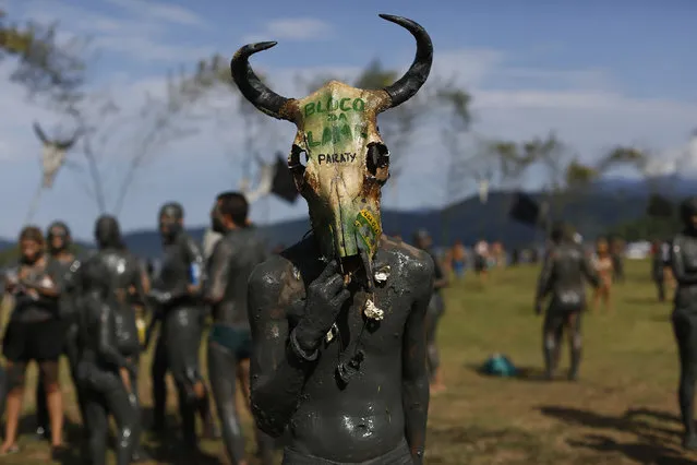 A mud covered reveler wearing a cow's skull as a mask poses for a photo during the traditional “Bloco da Lama” or “Mud Block” carnival party, in Paraty, Brazil, Saturday, February 14, 2015. (Photo by Leo Correa/AP Photo)