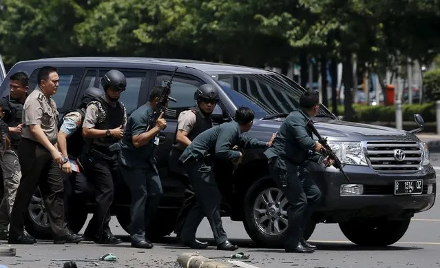 Indonesian police hold rifles while walking behind a car for protection in Jakarta January 14, 2016. (Photo by Reuters/Beawiharta)