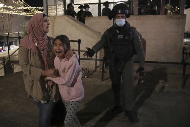 An Israeli police officer gestures to a Palestinian woman and her daughter, frightened by clashes outside of the Damascus Gate to the Old City of Jerusalem Tuesday, May 11, 2021. A confrontation between Israel and Hamas sparked by weeks of tensions in contested Jerusalem escalated Tuesday as Israel unleashed new airstrikes on Gaza while militants barraged Israel with hundreds of rockets. (Photo by Mahmoud Illean/AP Photo)
