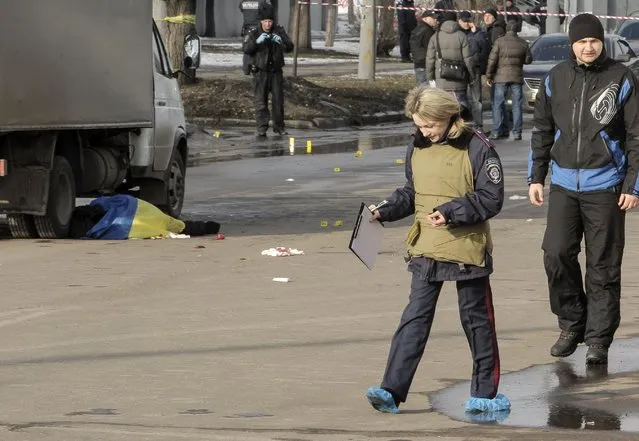ATTENTION EDITORS - VISUAL COVERAGE OF SCENES OF INJURY OR DEATH
A policewoman walks near the body of a victim covered by a Ukrainian national flag at the site of an attack in Kharkiv, February 22, 2015. At least two people were killed and 10 wounded on Sunday when an explosive device was thrown from a car into a crowd attending a peace rally in the northeastern Ukrainian city of Kharkiv, Ukrainian officials said.  REUTERS/Stanislav Belousov (UKRAINE - Tags: MILITARY CONFLICT CIVIL UNREST)