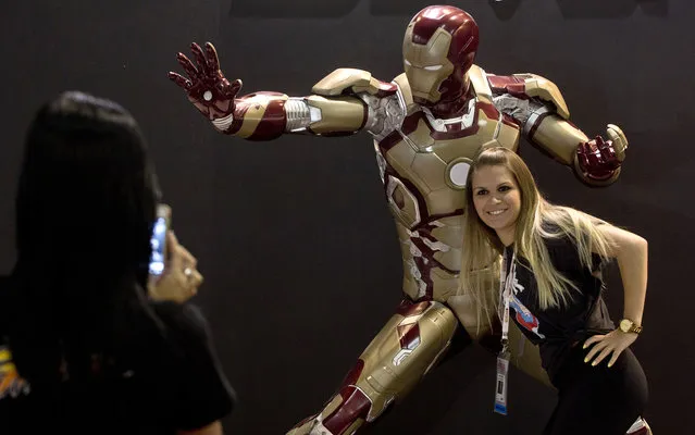 A woman poses next to the fictional character Iron Man displayed in the Brazil Game Show, an annual trade fair for the video games industry, the biggest of Latin America, in Sao Paulo, Brazil on October 25, 2013. (Photo by Nelson Almeida/AFP Photo)