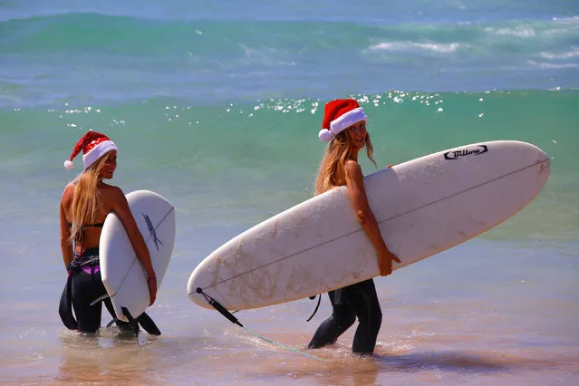 German tourists Mimi Wiebeling (L) and Pauline Lapetite carry surfboards as they walk into the surf wearing Christmas hats at Sydney's Bondi Beach on Christmas Day in Australia, December 25, 2016. (Photo by David Gray/Reuters)