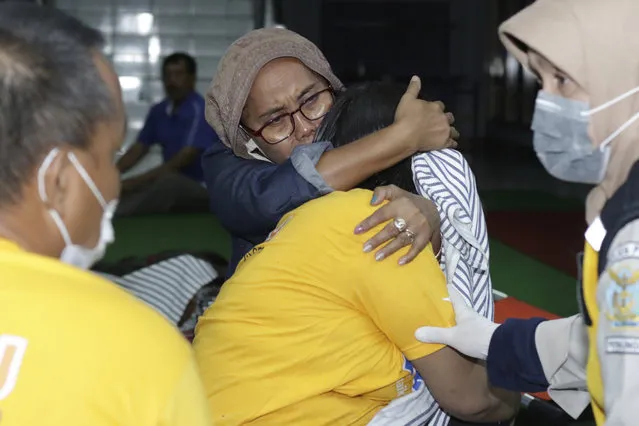 A relative embraces a survivor of the sinking ferry KMP Yunice at an evacuation point in Banyuwangi, East Java, Indonesia, early Wednesday, June 30, 2021. Rescuers searched into the night Tuesday for several missing people after the ferry sank in rough seas near Indonesia's resort island of Bali, killing a number of people, officials said. (Photo by AP Photo/Stringer)