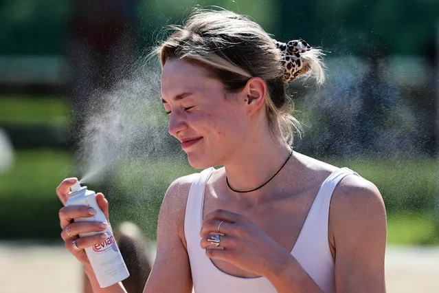 A woman sprays her face with thermal water at the Pokrovsky Bereg beach in Moscow, Russia on June 20, 2021. (Photo by Sergei Bobylev/TASS)