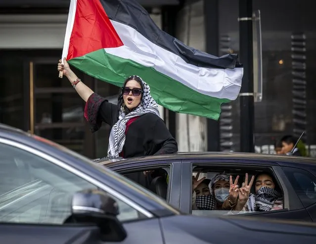 A woman waves a Palestinian flag while standing in a sunroof along K street as thousands gather downtown to protest the war in Gaza on November 4, 2023 in Washington, DC. (Photo by Bill O'Leary/The Washington Post)