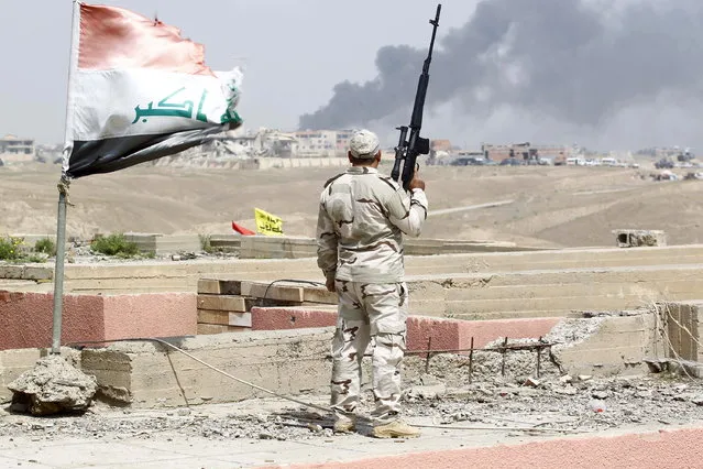 A member of the Iraqi security forces carries his weapon as he watches smoke rise from a scene of clashes between the Iraqi army and Islamic State militants in Tikrit, March 30, 2015. (Photo by Alaa Al-Marjani/Reuters)