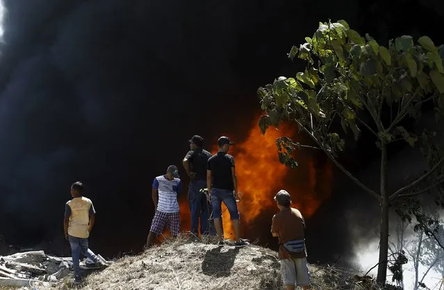 People watch a fire at an illegal garbage dump after neighbors decided to set fire to it, to prevent the spread of the mosquito-borne Zika virus, in a slum of San Jose, Costa Rica February 8, 2016. (Photo by Juan Carlos Ulate/Reuters)