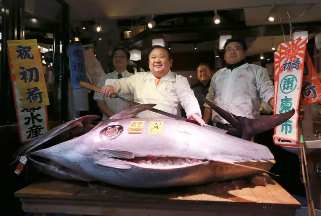 Kiyoshi Kimura, center, president of Kiyomura Co., poses with the bluefin tuna he made a winning bid at the annual New Year auction, at his Sushi Zanmai restaurant near Tsukiji fish market in Tokyo, early Thursday, January 5, 2017. The Japanese sushi chain boss bid a winning 74.2 million yen ($632,000) Thursday for the 212 kilogram (466 pound) bluefin tuna in what may be Tsukiji market's last auction at its current site in downtown Tokyo. (Photo by Eugene Hoshiko/AP Photo)