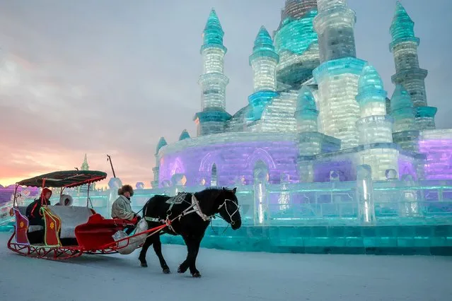 Visitors sit in a horse-drawn carriage in front of the ice sculptures at the Ice and Snow World during the annual Harbin International Ice and Snow Sculpture Festival, in Harbin, Heilongjiang province, China, 04 January 2019. Some 120,000 cubic meters of ice and 111,000 cubic meters of snow were used to build the Harbin Ice and Snow World where the festival will last for about three months. (Photo by Roman Pilipey/EPA/EFE)