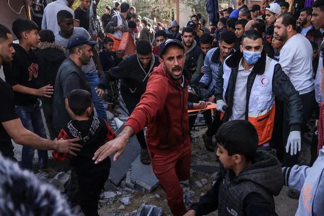 A Palestinian medic and civilians carry an injured man after an Israeli strike on Rafah, in the southern Gaza Strip on November 23, 2023, amid continuing battles between Israel and the Palestinian militant group Hamas. (Photo by Said Khatib/AFP Photo)