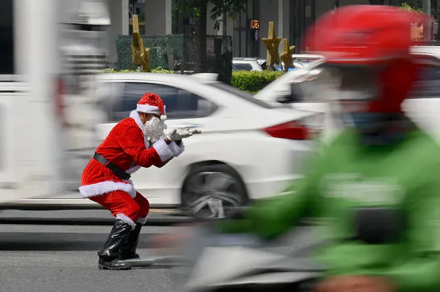 Traffic enforcer Ramiro Hinojas, dressed as Santa Claus as part of the festive season, directs vehicles along Macapagal Avenue in Pasay, Metro Manila on November 28, 2023. (Photo by Jam Sta Rosa/AFP Photo)