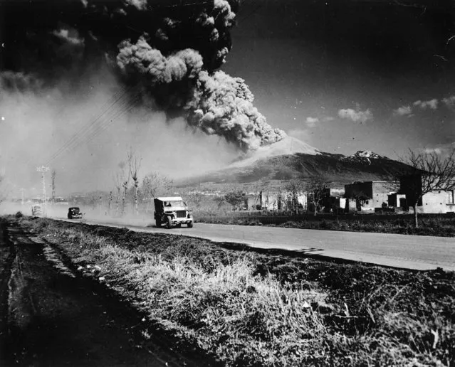 With Mt. Vesuvius smoking and spewing ash in the background, an Army jeep is seen speeding away from the inferno, as the volcano erupts shortly after the arrival of the Allied forces in Naples, on March 17, 1944. (Photo by AP Photo)