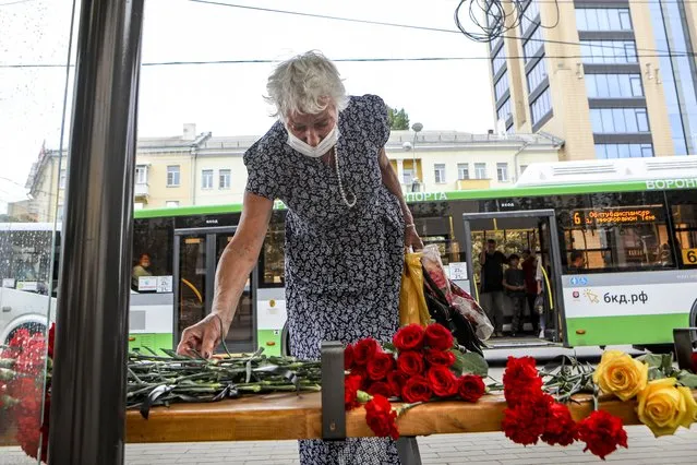 A woman lays flowers at a bus stop in memory of people died from injuries they sustained in the explosion near a side of an explosion on a city bus in Voronezh, about 450 kilometers (280 miles) south of Moscow, Russia, on Friday, August 13, 2021. (Photo by Kristina Brazhnikova/AP Photo)