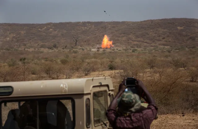 In this photo taken on Thursday, February 18, 2016,  a participant, foreground, takes photos as an car explodes during U.S-led Flintlock military training in Thies, Senegal. The training for 50 Senegalese police, gendarmes, customs and judicial officials is part of the annual U.S.-led Flintlock exercises, a more than decade-old effort to help Africans counter threats from extremist militants. (Photo by Vincent Tremeau/AP Photo)