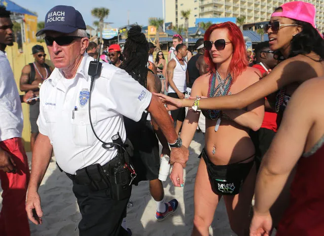 In this March, 2015 photo, women are led off the beach by police after allegedly exposing themselves during spring break festivities in Panama City Beach, Fla. Tourism officials who survived Florida's other Spring Break fevers are ready to help Panama City Beach improve its image. (Heather Leiphart/News Herald via AP Photo)