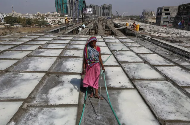 A labourer sprays water on a concrete at a construction site on the outskirts of Ahmedabad, India, February 26, 2016. India expects its economy to grow 7-7.75 percent in the fiscal year to March 2017, a key government report said on Friday, ahead of the presentation of the annual budget by Finance Minister Arun Jaitley on Monday. (Photo by Amit Dave/Reuters)